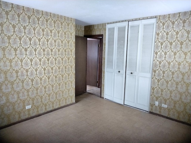 unfurnished bedroom featuring a closet, wallpapered walls, and baseboards