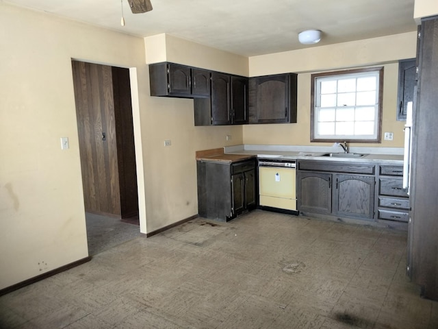 kitchen featuring light floors, dishwasher, baseboards, and a sink