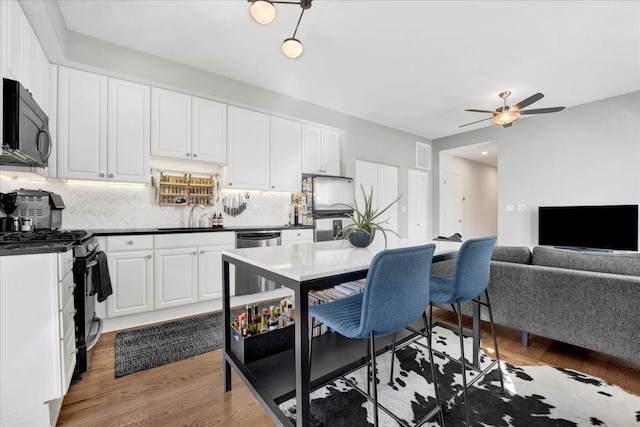 kitchen featuring dark countertops, white cabinetry, appliances with stainless steel finishes, and open floor plan