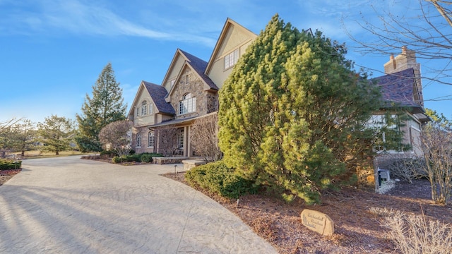 view of property exterior with decorative driveway and stone siding