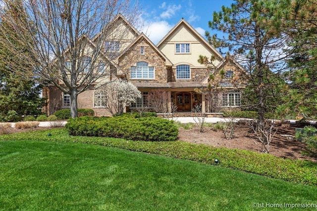 view of front facade with a front yard, stone siding, and stucco siding