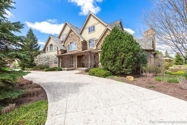 view of front of house with concrete driveway, stone siding, and stucco siding