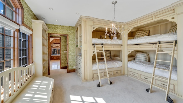 carpeted bedroom with an inviting chandelier and wallpapered walls