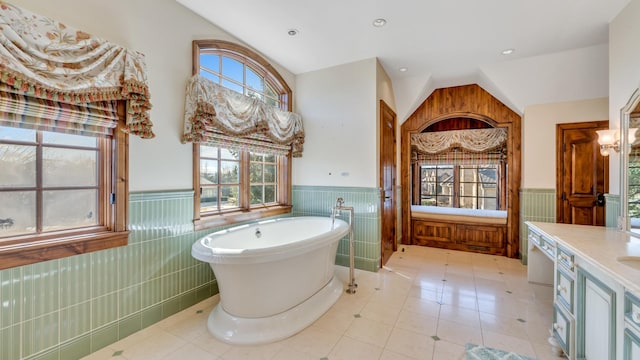 full bathroom with a wainscoted wall, a freestanding bath, lofted ceiling, recessed lighting, and vanity