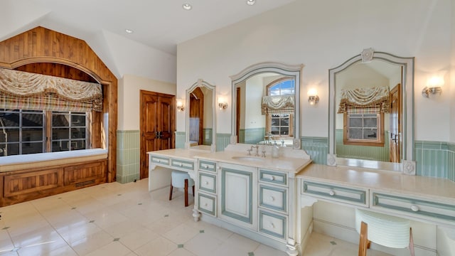 full bathroom featuring tile patterned floors, a wainscoted wall, lofted ceiling, and vanity