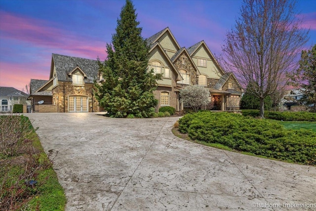 view of front of home with french doors, stone siding, and concrete driveway