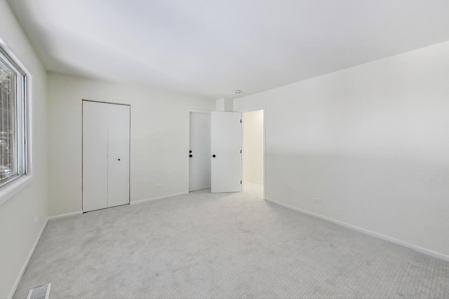 unfurnished bedroom with baseboards, multiple windows, visible vents, and light colored carpet