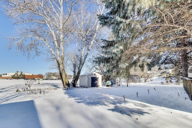 snowy yard featuring a storage shed and an outbuilding