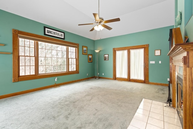 unfurnished living room featuring a tile fireplace, a wealth of natural light, light colored carpet, and ceiling fan