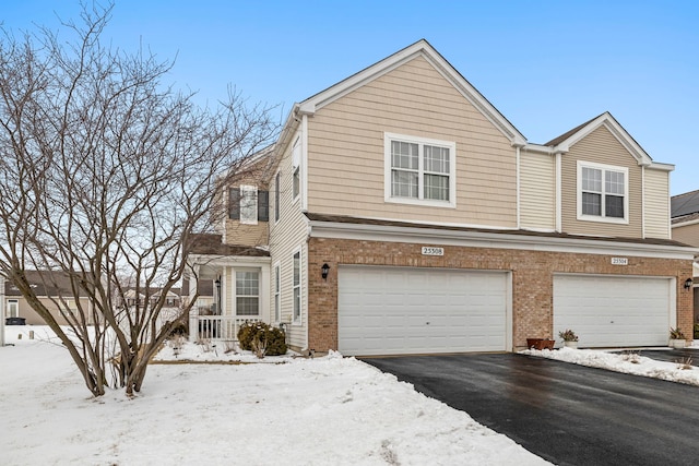 view of front facade featuring aphalt driveway, brick siding, and a garage