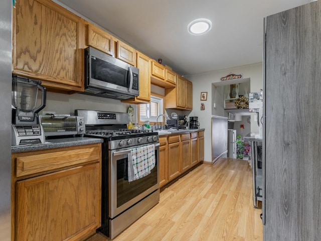 kitchen with sink, light wood-type flooring, and appliances with stainless steel finishes