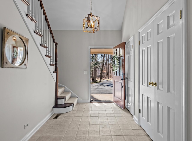 entrance foyer with light tile patterned flooring, baseboards, an inviting chandelier, and stairs