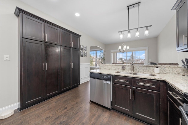 kitchen featuring arched walkways, a sink, stainless steel dishwasher, dark wood finished floors, and decorative light fixtures