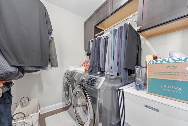 washroom featuring cabinet space, baseboards, and separate washer and dryer