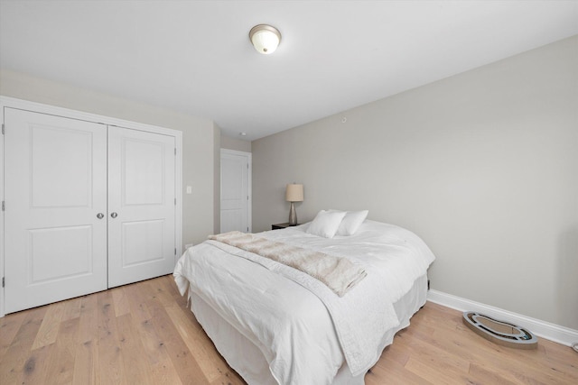 bedroom with a closet, baseboards, and light wood finished floors