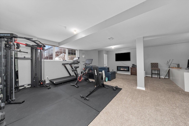 workout area with a glass covered fireplace and baseboards