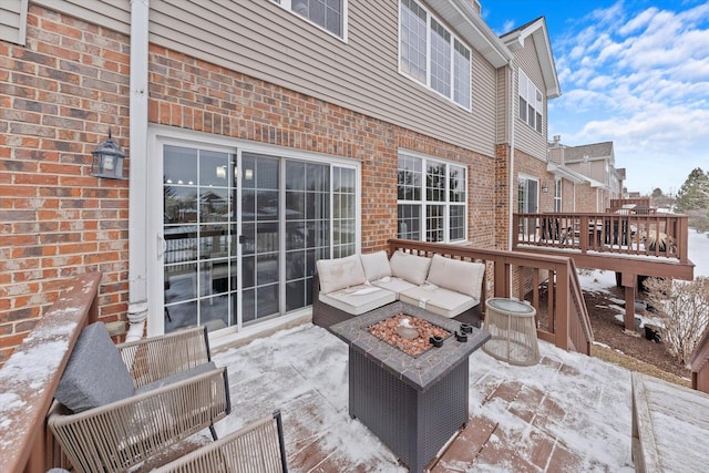 snow covered patio with an outdoor living space with a fire pit and a wooden deck