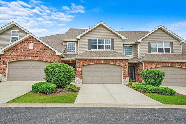 view of front of home featuring a garage, concrete driveway, roof with shingles, and brick siding