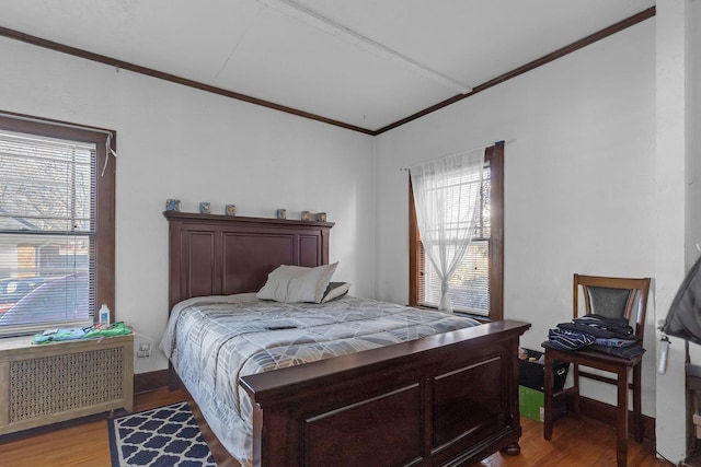 bedroom with light wood-style floors, radiator heating unit, and ornamental molding