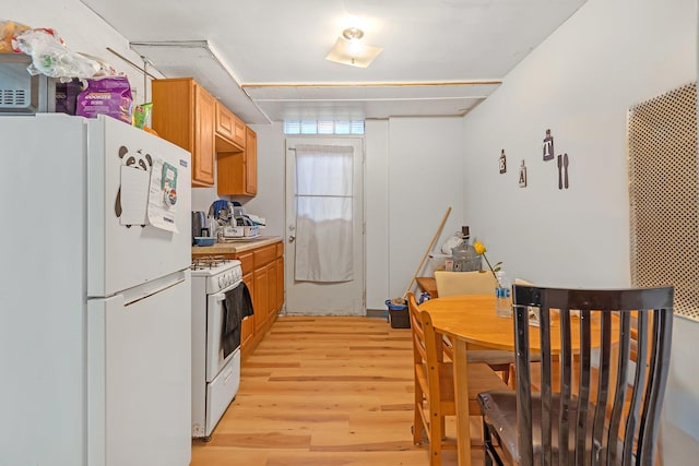 kitchen with light wood finished floors, light countertops, and white appliances