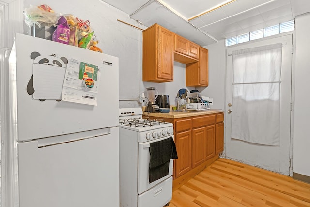 kitchen with light wood-type flooring, white appliances, and light countertops