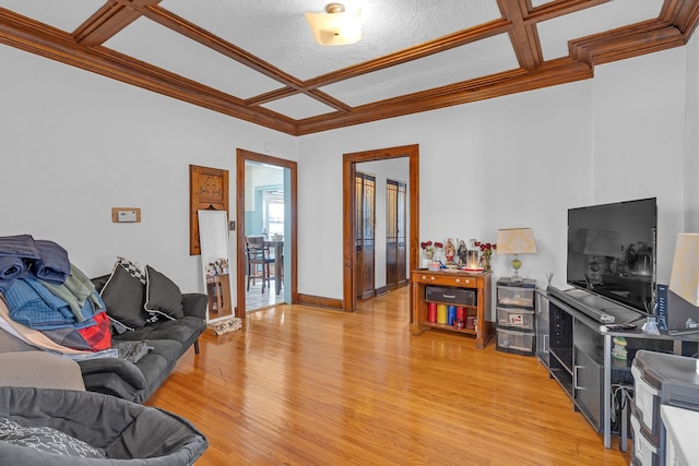 living room featuring light wood-style floors, coffered ceiling, ornamental molding, and baseboards