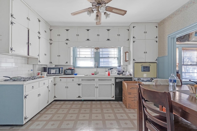 kitchen featuring light floors, stainless steel appliances, light countertops, white cabinetry, and a sink