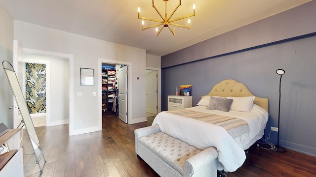 bedroom with a walk in closet, dark wood-type flooring, a chandelier, and a closet