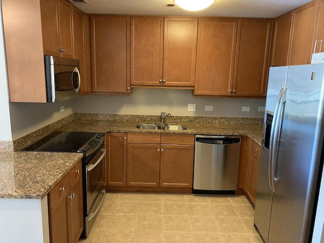 kitchen featuring stone countertops, appliances with stainless steel finishes, sink, and light tile patterned floors