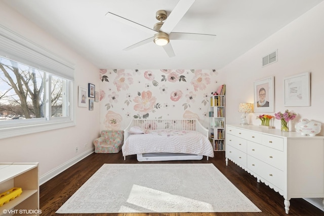 bedroom featuring visible vents, dark wood-type flooring, ceiling fan, baseboards, and wallpapered walls