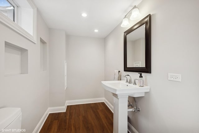 bathroom with baseboards, toilet, wood finished floors, a sink, and recessed lighting