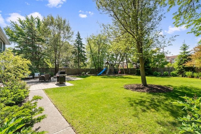 view of yard featuring a patio area, a fenced backyard, and a playground