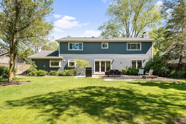 back of property featuring a patio area, fence, a chimney, and a lawn