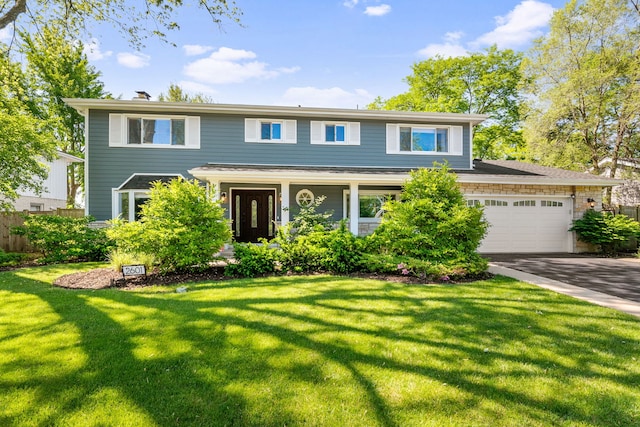 view of front of home featuring driveway, an attached garage, and a front lawn