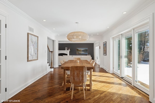 dining space with ornamental molding, visible vents, and wood finished floors