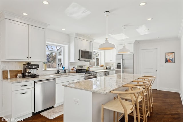 kitchen with a center island, pendant lighting, stainless steel appliances, white cabinetry, and a sink