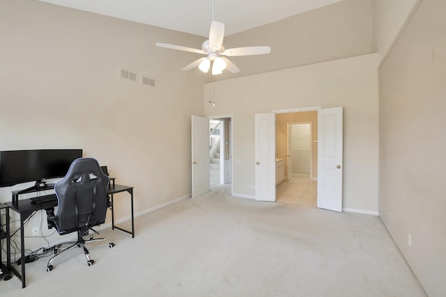 carpeted home office with a ceiling fan, a towering ceiling, visible vents, and baseboards