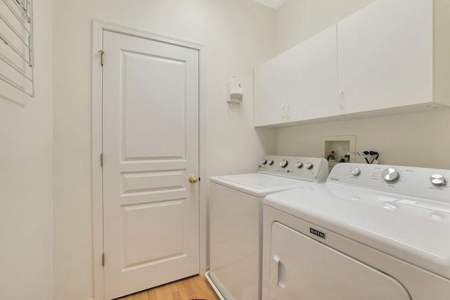 laundry area featuring cabinet space, light wood-style flooring, and separate washer and dryer