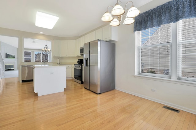 kitchen with a notable chandelier, stainless steel appliances, visible vents, light countertops, and plenty of natural light