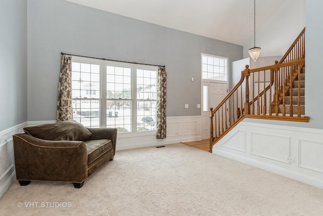 living area with carpet, plenty of natural light, stairs, and a decorative wall