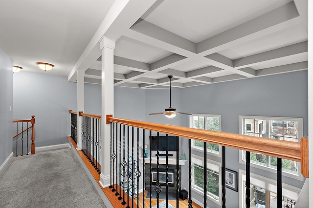 corridor with baseboards, coffered ceiling, beamed ceiling, and an upstairs landing