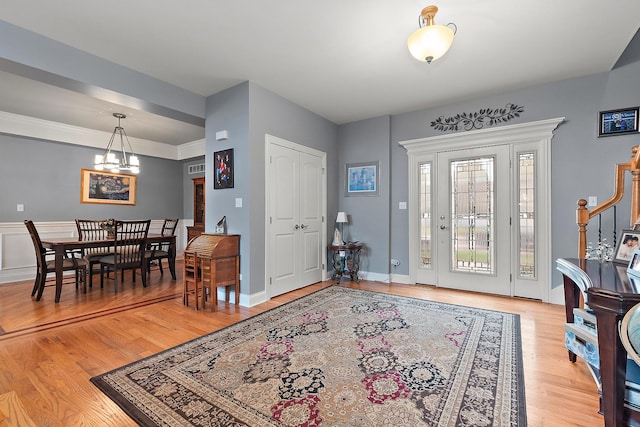 entrance foyer with a chandelier, light wood finished floors, and baseboards