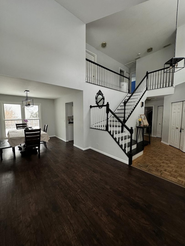 interior space with a towering ceiling, parquet floors, and a notable chandelier