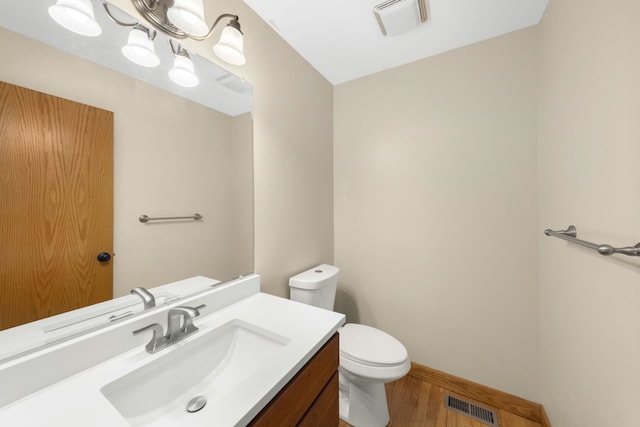 bathroom with wood-type flooring, vanity, a chandelier, and toilet