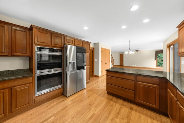 kitchen featuring a chandelier, light wood-type flooring, stainless steel appliances, and pendant lighting