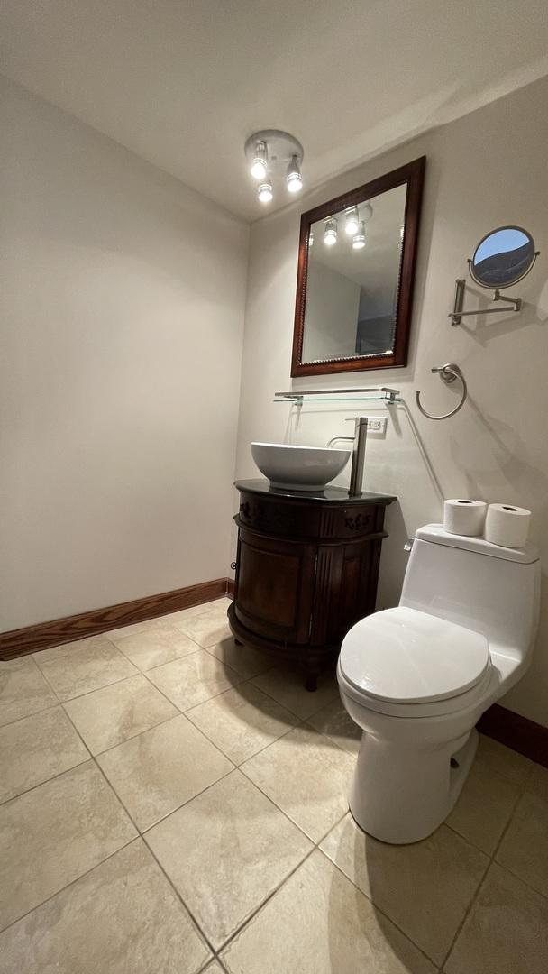 half bathroom with baseboards, vanity, toilet, and tile patterned floors