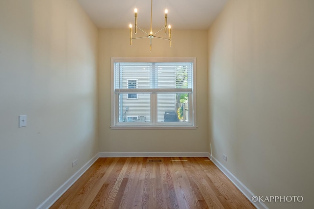 empty room featuring a chandelier and light hardwood / wood-style flooring