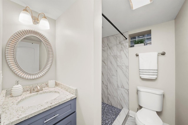 bathroom featuring vanity, toilet, and a tile shower