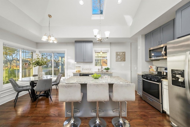 kitchen featuring appliances with stainless steel finishes, hanging light fixtures, and gray cabinetry