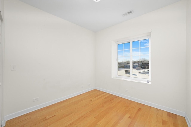 unfurnished room featuring baseboards, visible vents, and wood finished floors